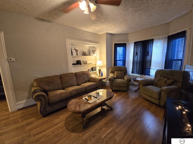 living room with baseboards, wood finished floors, a textured wall, a textured ceiling, and a ceiling fan