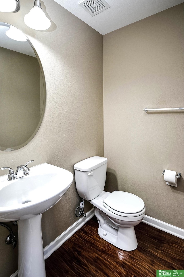 half bathroom featuring visible vents, baseboards, toilet, and wood finished floors