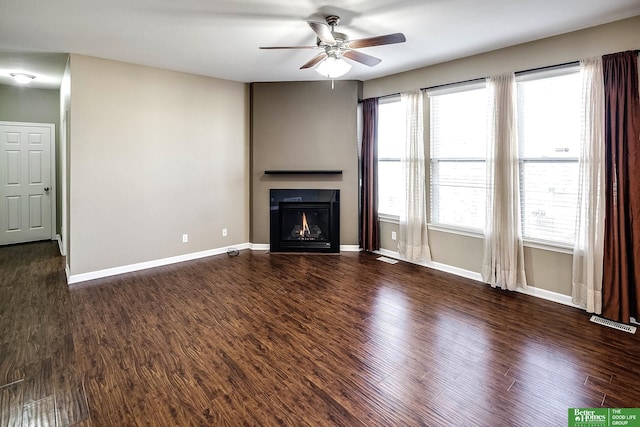 unfurnished living room featuring baseboards, a lit fireplace, wood finished floors, and a ceiling fan