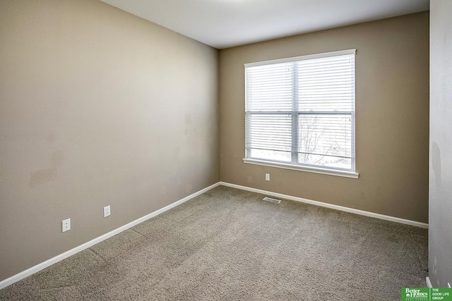 empty room featuring carpet flooring, visible vents, and baseboards