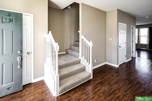 foyer entrance with stairway, wood finished floors, and baseboards