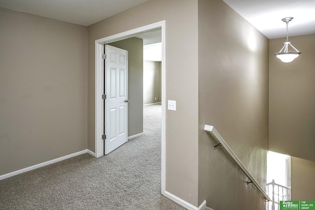 hall with baseboards, an upstairs landing, and carpet