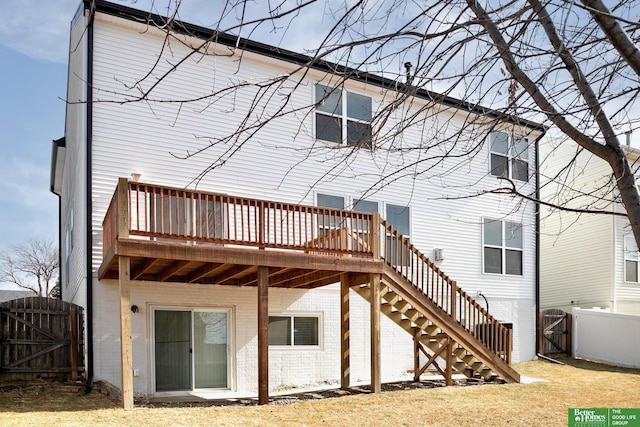 rear view of property with a wooden deck, fence, brick siding, and a gate