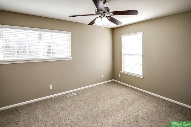 carpeted spare room with baseboards, visible vents, and ceiling fan