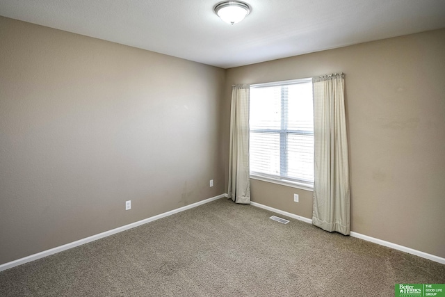 carpeted spare room featuring visible vents and baseboards