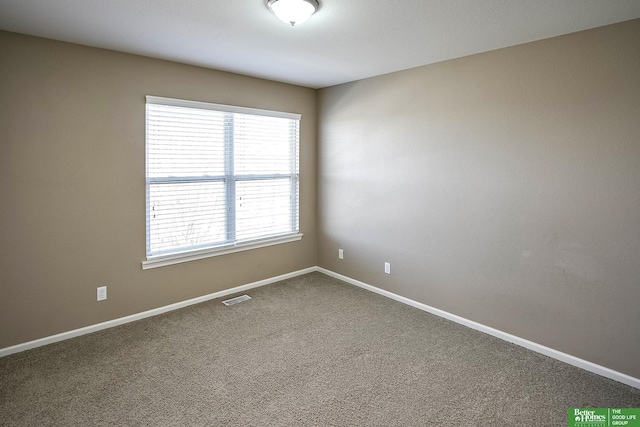 empty room with visible vents, baseboards, and dark carpet