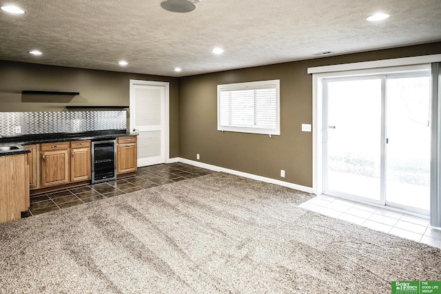 kitchen with dark countertops, recessed lighting, beverage cooler, and a textured ceiling