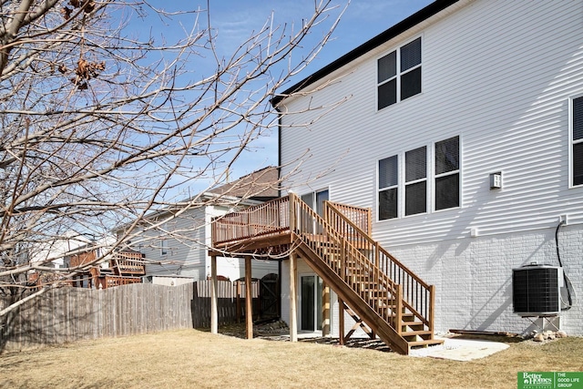 back of property featuring fence, stairway, a wooden deck, a lawn, and cooling unit