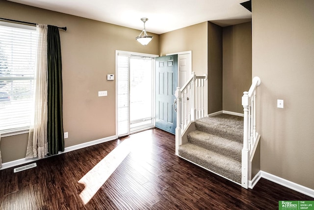 entrance foyer with visible vents, baseboards, wood finished floors, and stairs