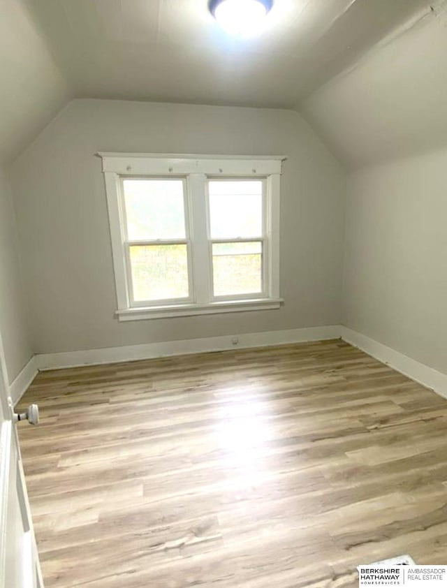 additional living space featuring lofted ceiling, baseboards, and light wood-type flooring