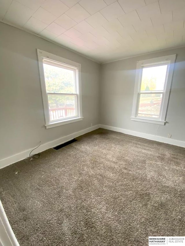 carpeted empty room featuring baseboards and visible vents