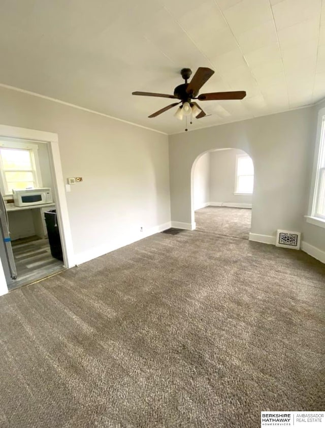 spare room featuring visible vents, arched walkways, carpet, and a ceiling fan