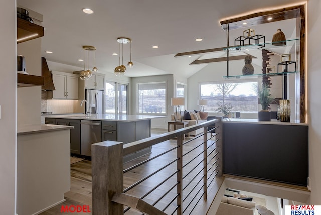 kitchen featuring a kitchen island with sink, stainless steel appliances, decorative backsplash, light countertops, and open floor plan