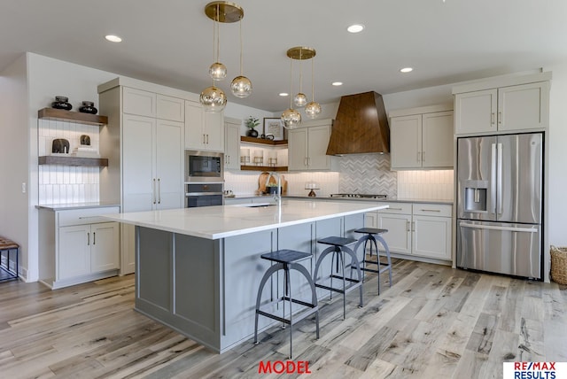 kitchen featuring light countertops, appliances with stainless steel finishes, light wood-style floors, custom exhaust hood, and open shelves