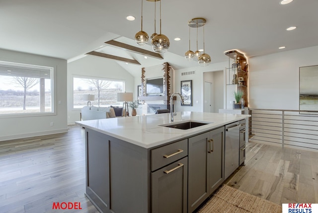 kitchen featuring vaulted ceiling with beams, gray cabinets, a sink, open floor plan, and light wood-type flooring