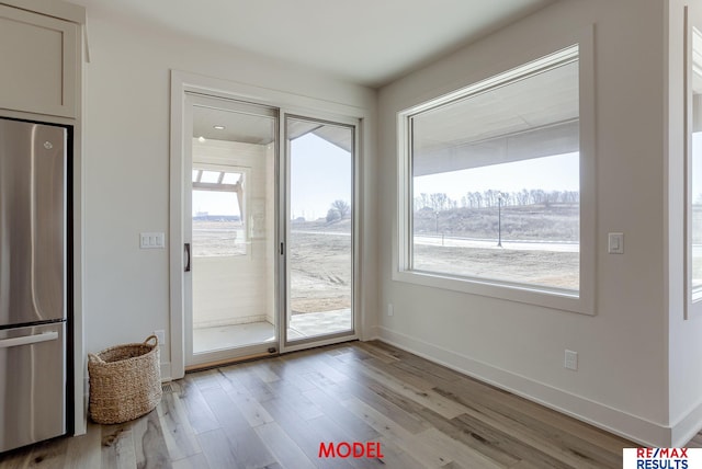 doorway featuring a wealth of natural light, baseboards, and light wood-style flooring