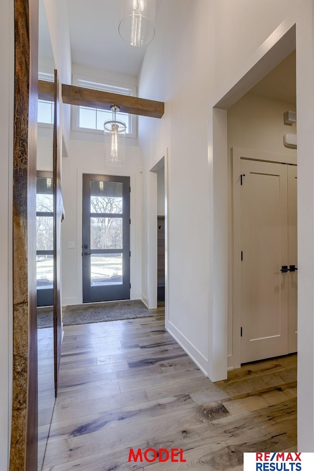 entryway with a high ceiling, light wood-style flooring, and baseboards