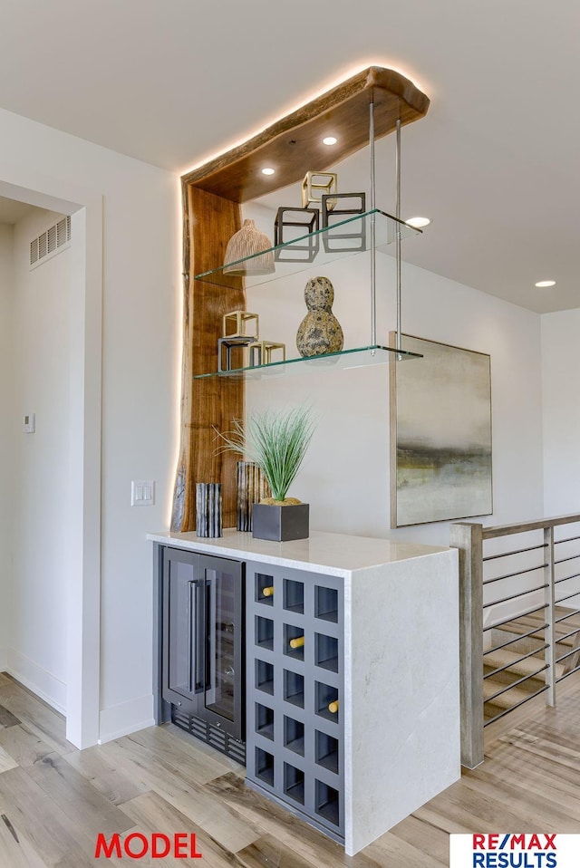 bar with visible vents, wine cooler, baseboards, and wood finished floors