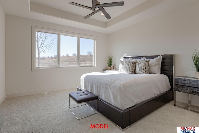 carpeted bedroom featuring ceiling fan, a raised ceiling, and baseboards