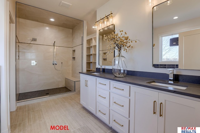 full bathroom featuring double vanity, tiled shower, visible vents, and a sink