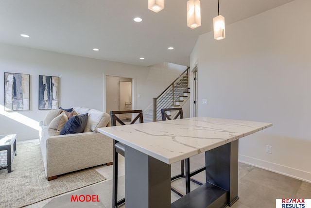 kitchen featuring a breakfast bar, decorative light fixtures, a kitchen island, recessed lighting, and light stone countertops