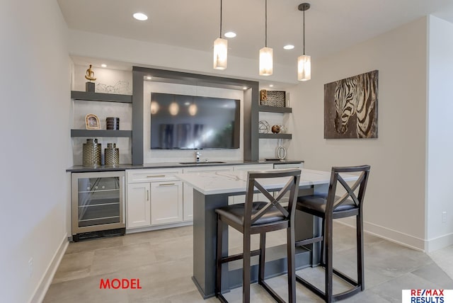 bar featuring a sink, baseboards, wine cooler, and hanging light fixtures