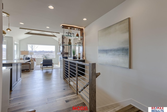 hallway with wood finished floors, baseboards, lofted ceiling, recessed lighting, and an upstairs landing