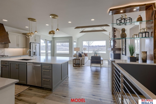 kitchen featuring wood finished floors, a sink, gray cabinetry, light countertops, and stainless steel appliances