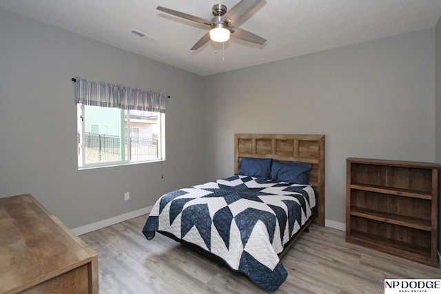 bedroom with wood finished floors, visible vents, and baseboards