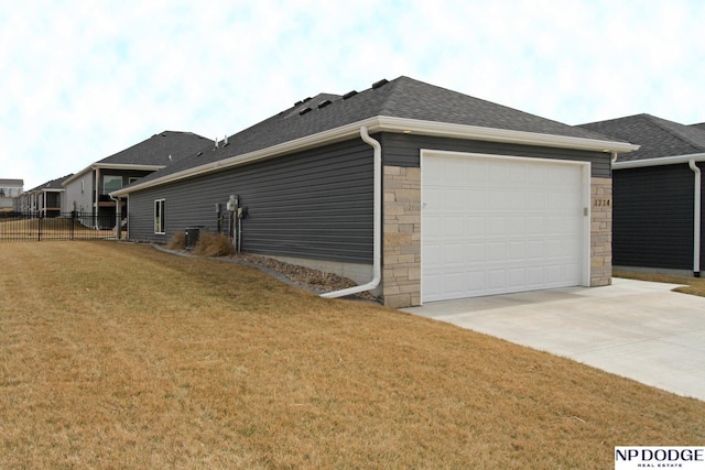 view of home's exterior featuring fence, a garage, a yard, stone siding, and driveway