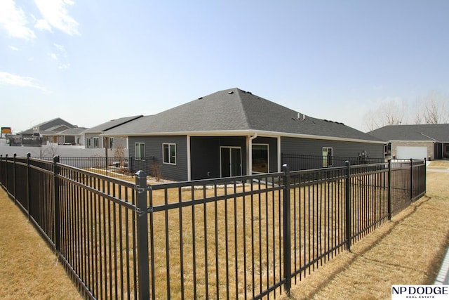 rear view of property featuring a shingled roof and a fenced backyard