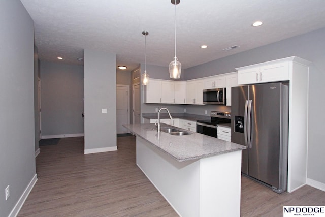 kitchen with white cabinets, appliances with stainless steel finishes, light wood-style floors, and a sink