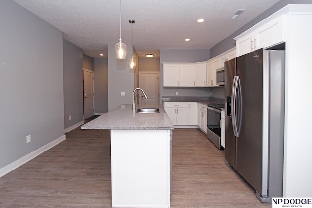 kitchen with baseboards, a kitchen island with sink, a sink, appliances with stainless steel finishes, and light wood-type flooring