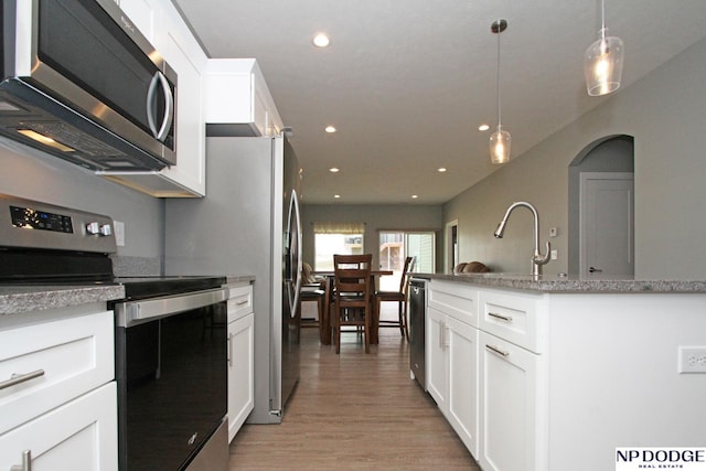 kitchen featuring recessed lighting, white cabinets, light wood-style floors, appliances with stainless steel finishes, and pendant lighting