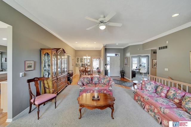 living room with ceiling fan with notable chandelier, crown molding, baseboards, and visible vents