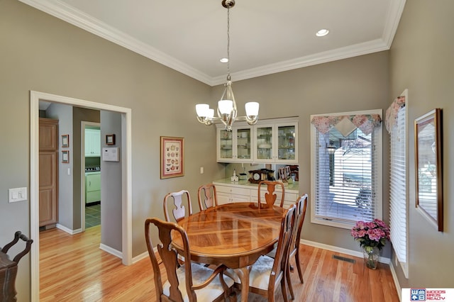 dining area featuring visible vents, light wood-style floors, an inviting chandelier, and crown molding