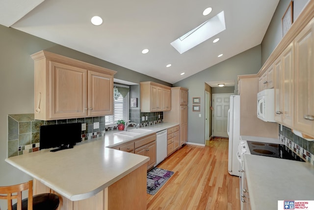 kitchen with white appliances, a peninsula, light brown cabinets, and light countertops