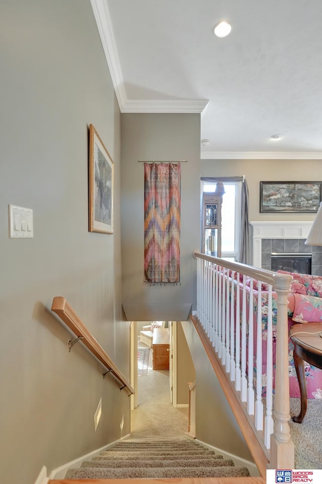 stairs with crown molding, a fireplace, and carpet floors