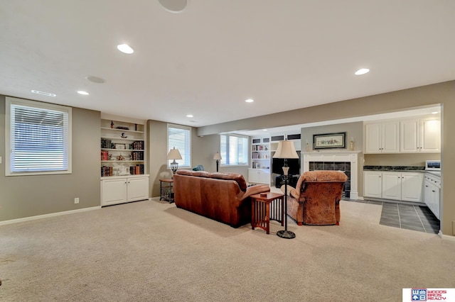 living room featuring built in features, carpet, and a tiled fireplace