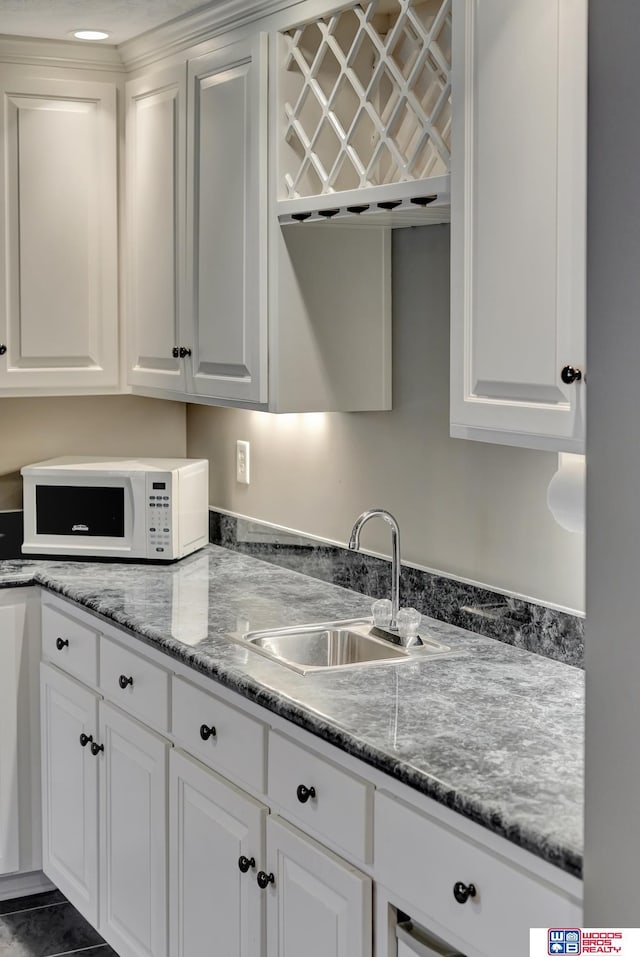 kitchen with white microwave, white cabinets, and a sink