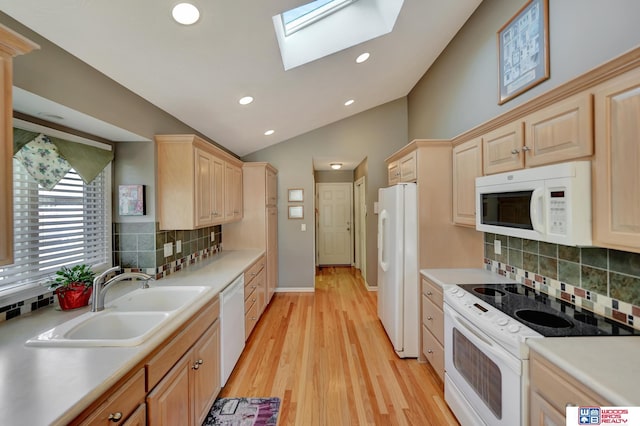 kitchen with a sink, white appliances, vaulted ceiling with skylight, and light brown cabinets