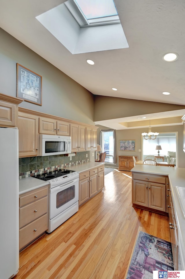 kitchen featuring light brown cabinetry, lofted ceiling with skylight, white appliances, and light countertops