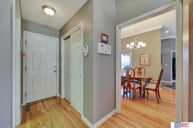 foyer featuring visible vents, ornamental molding, light wood finished floors, baseboards, and a chandelier