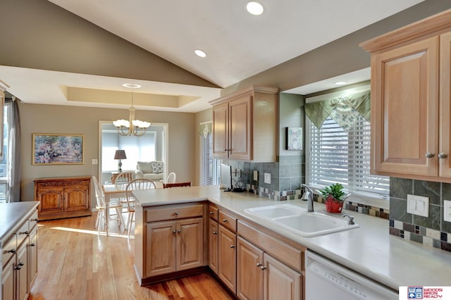 kitchen with light wood-type flooring, a sink, a peninsula, white dishwasher, and light countertops