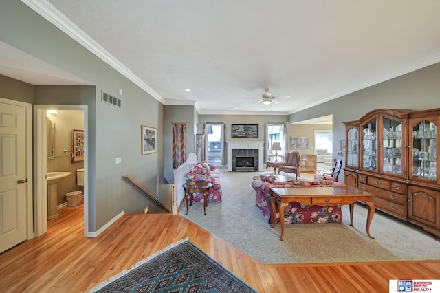 living area featuring wood finished floors, baseboards, visible vents, a tile fireplace, and ceiling fan