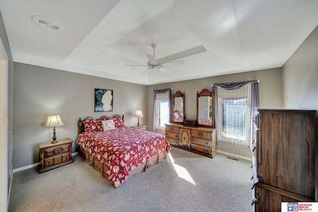 carpeted bedroom with a raised ceiling, a ceiling fan, baseboards, and visible vents