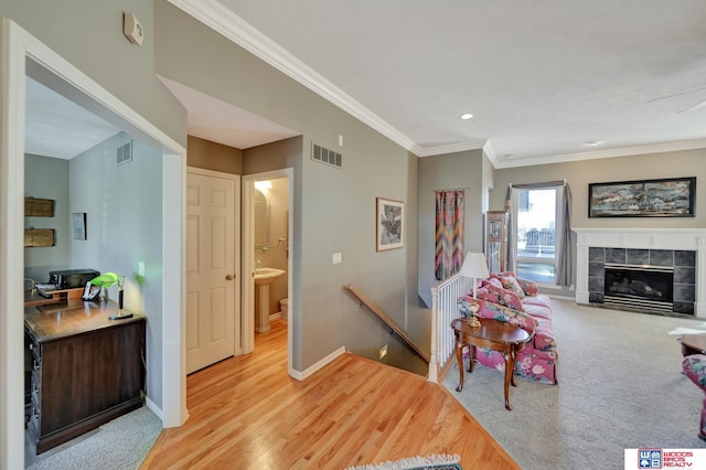 living room featuring visible vents, baseboards, ornamental molding, and a tiled fireplace