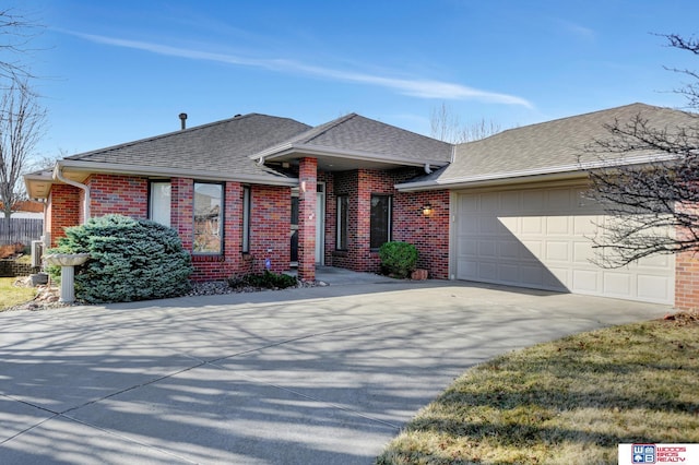 view of front facade featuring concrete driveway, a garage, brick siding, and roof with shingles