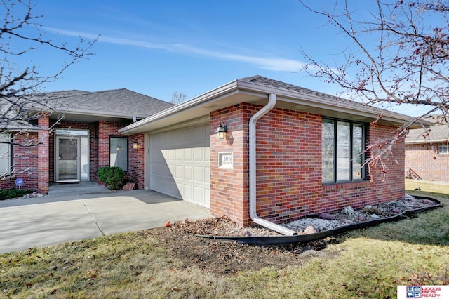 view of front of home with brick siding, an attached garage, concrete driveway, and a shingled roof