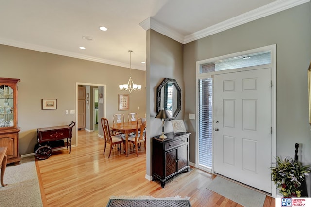 foyer featuring a notable chandelier, baseboards, crown molding, and light wood-style floors